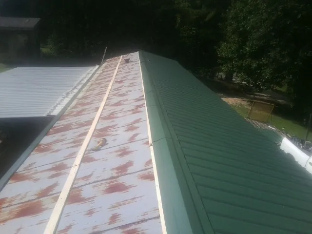 Old rusted panels beside newly installed green metal roofing — Wind Damage Roof Repair by Roofing Brothers in Newtown Square