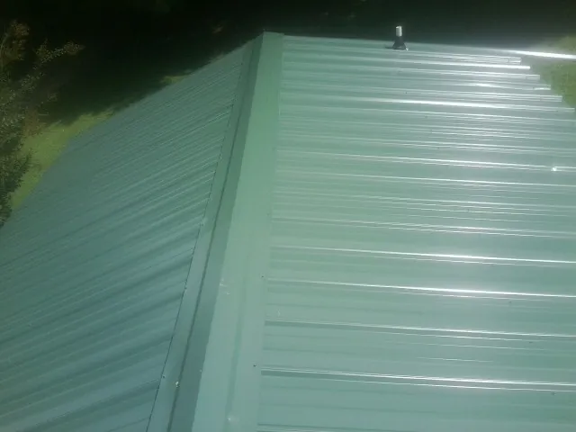 New green metal panels meeting at the ridge of a roof — Flat Roof Repair work by our crew in Newtown Square