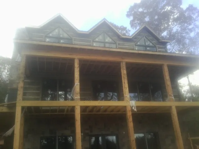 Dormers and porch framing on a large log home under construction — Roof Coating work by our crew in Newtown Square