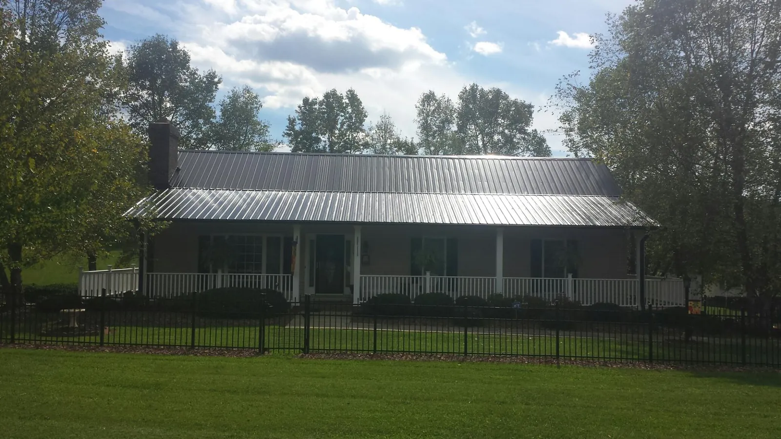 Gray metal roof on a brick ranch with a full width front porch — Gutter Guard Installation work by our crew in Newtown Square
