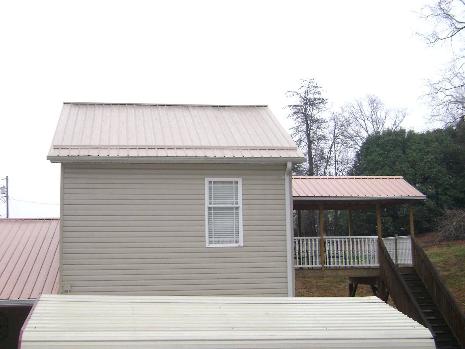 Tan metal roofs on a two story addition and attached porch, from a Roof Replacement job in Newtown Square