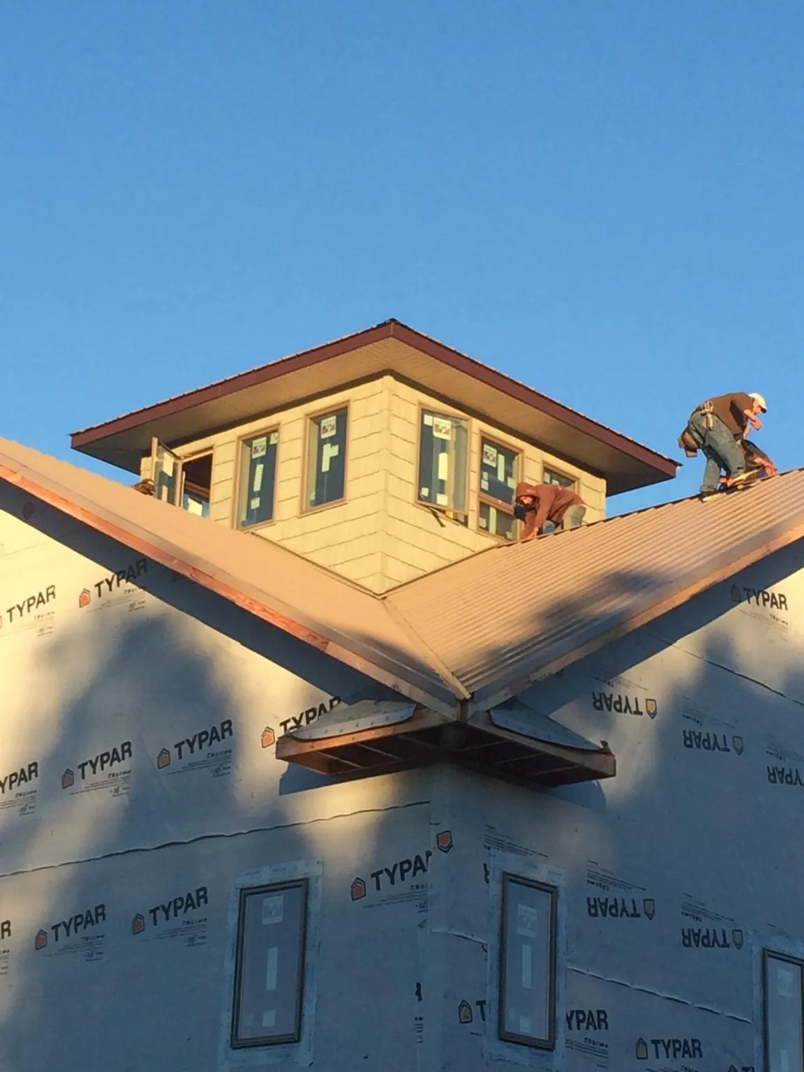 Roofers working around a rooftop cupola on a new metal roof at sunset — Roof Waterproofing in Newtown Square by Roofing Brothers